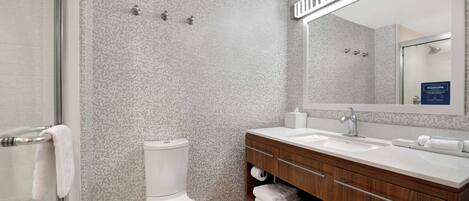A modern bathroom with a toilet, sink, and mirror.