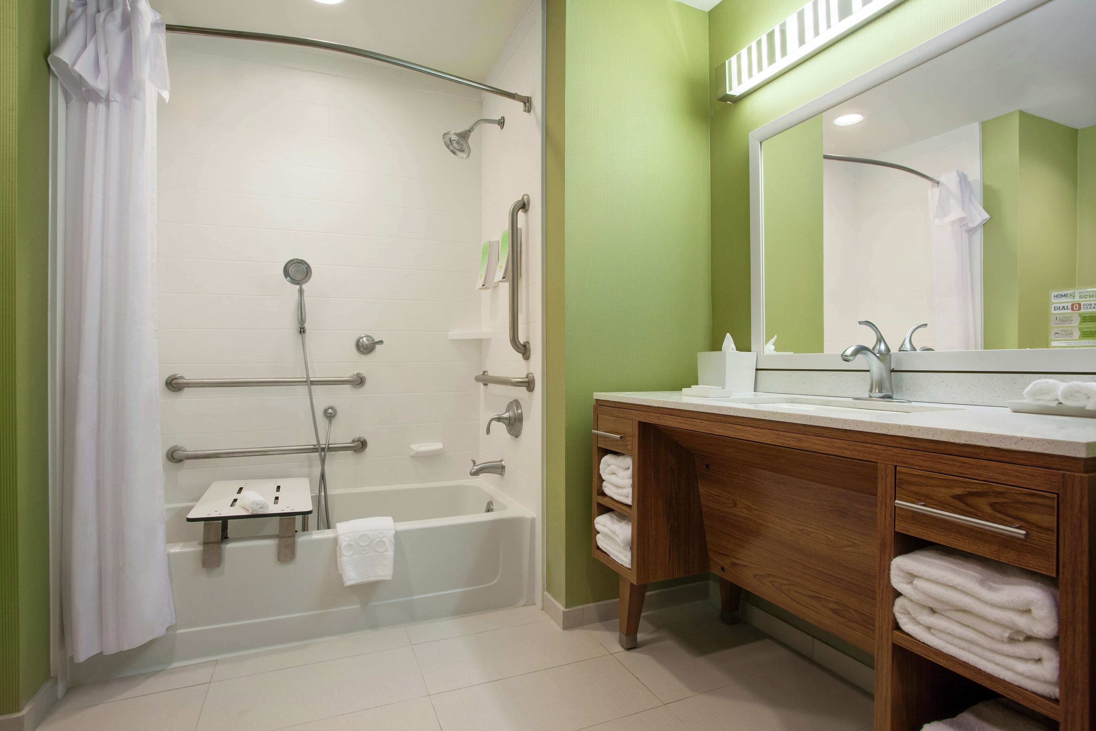 A bathroom with a bathtub, shower, vanity with a mirror, and a towel rack.