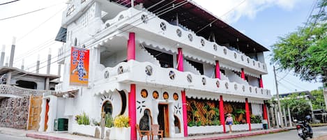 A two-story building with a distinctive architectural style, featuring a balcony with chairs and a red column.