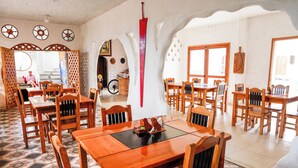 Un área de comedor con mesas y sillas de madera, un adorno central y un piso con diseño.