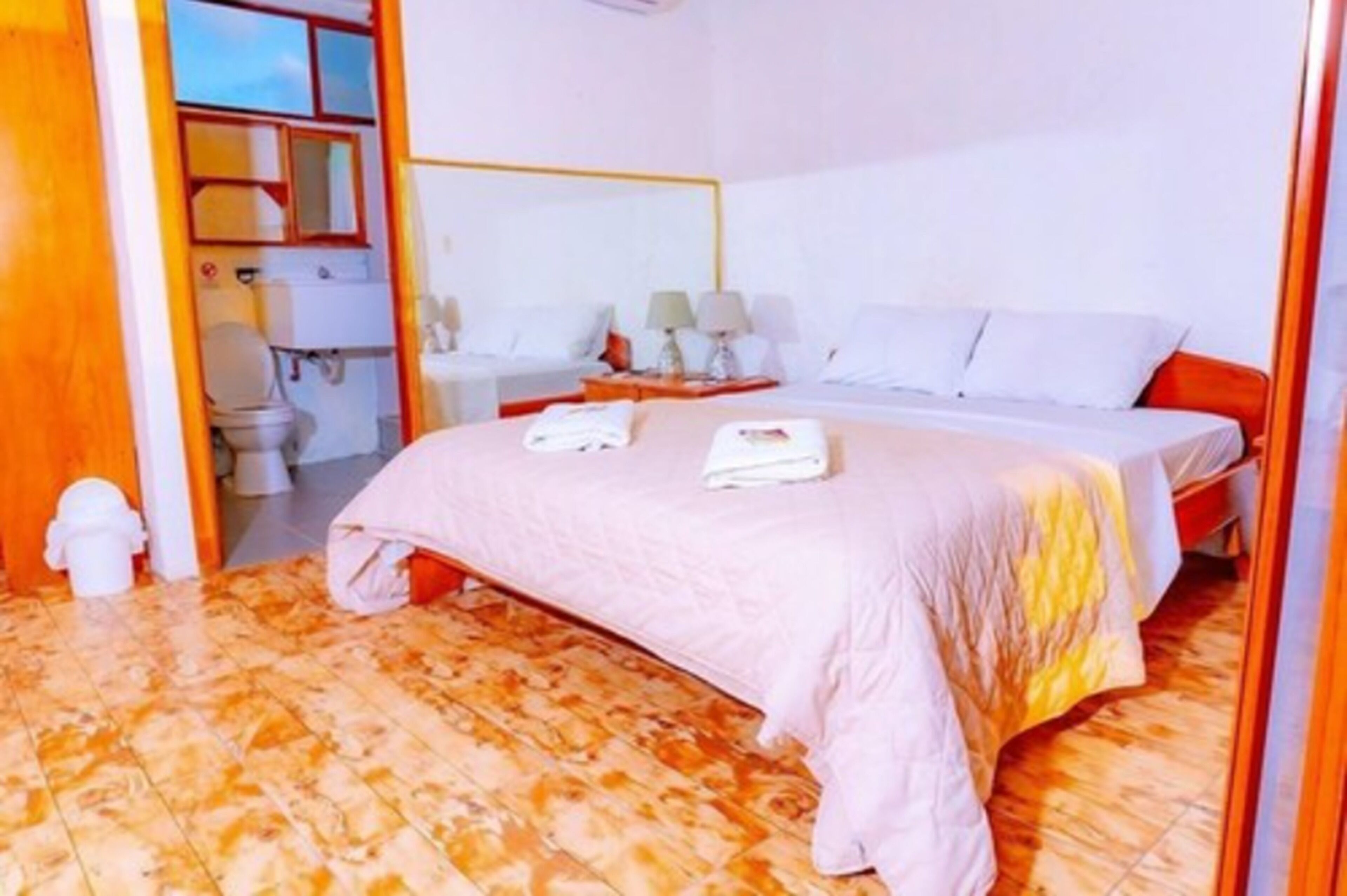 Une chambre d’hôtel comprenant un lit, des tables de chevet, une salle de bain et donnant sur l’extérieur.