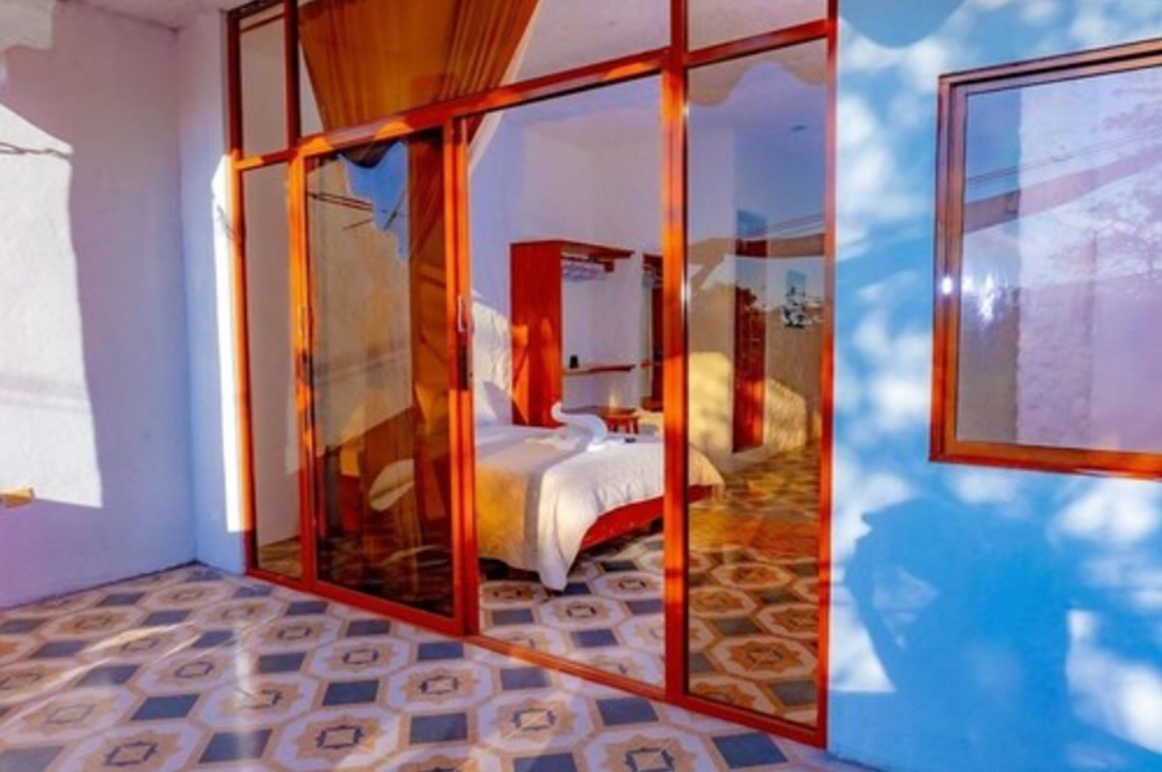 A room with a bed, a window, and a patterned floor.