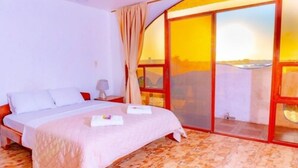 Un dormitorio con una cama grande, una mesita de noche, una ventana con vistas y una puerta corredera de vidrio.