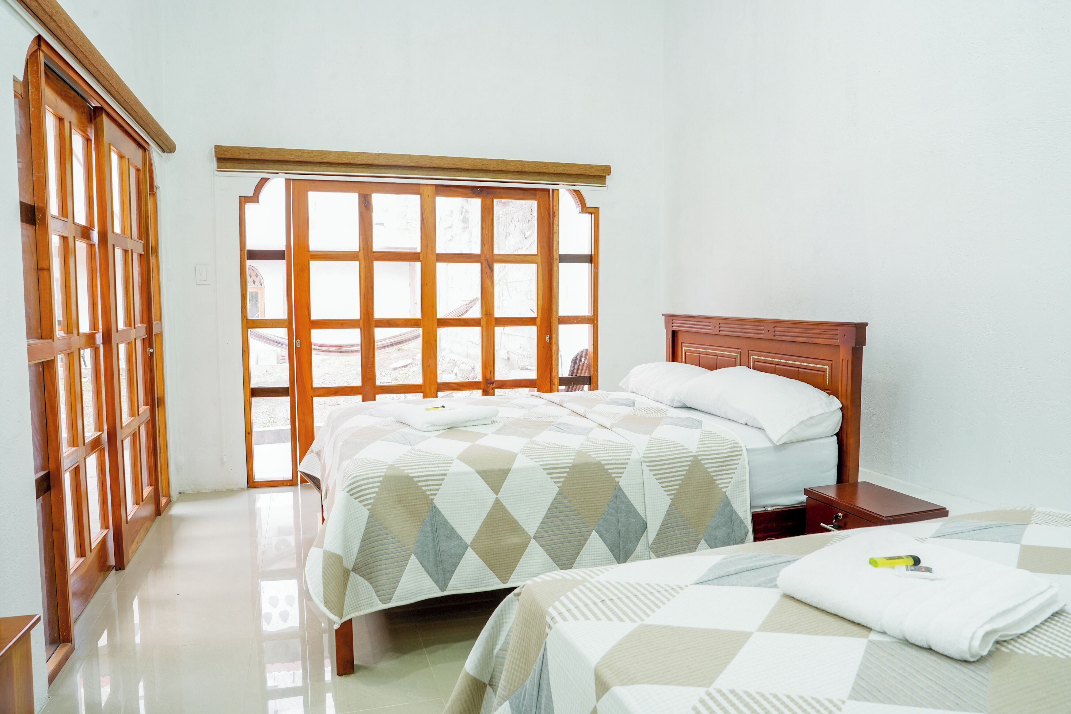 Een hotelkamer met een groot raam, een bed met een houten hoofdeinde en een nachtkastje.