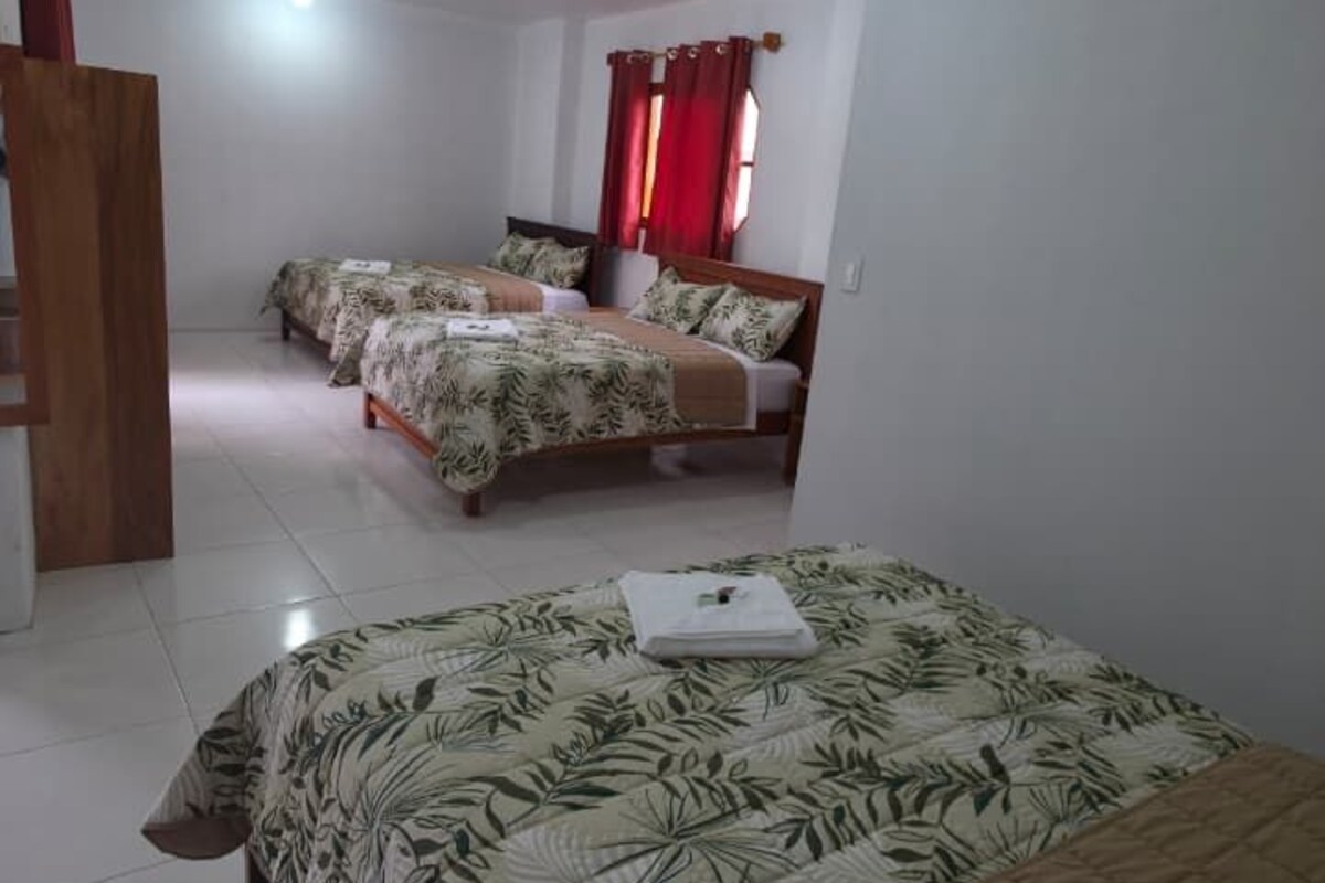 A bedroom with a large bed, two smaller beds, and a wooden wardrobe.