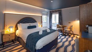 Una habitación de hotel moderna con una cama grande, mesitas de noche, un escritorio y una silla.