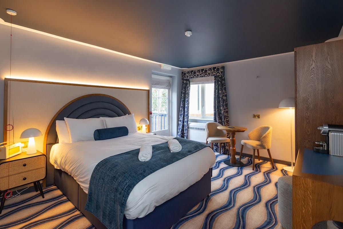 A modern hotel room with a large bed, bedside tables, a desk, and a chair.