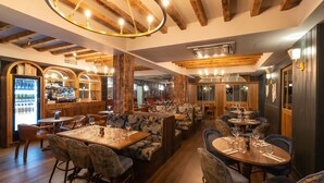 Un restaurante con vigas de madera, mesas con cubierta de mármol y asientos tipo cabina acolchados.