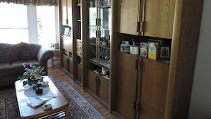 A living room with a wooden cabinet, a sofa, and a coffee table. - Tucked Inn the Harbour Bed & Breakfast (Tay)