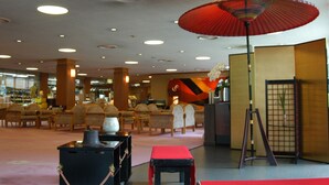 Een ruime lobby met verschillende zithoeken, een grote rode paraplu en een presentatie van keramiek.