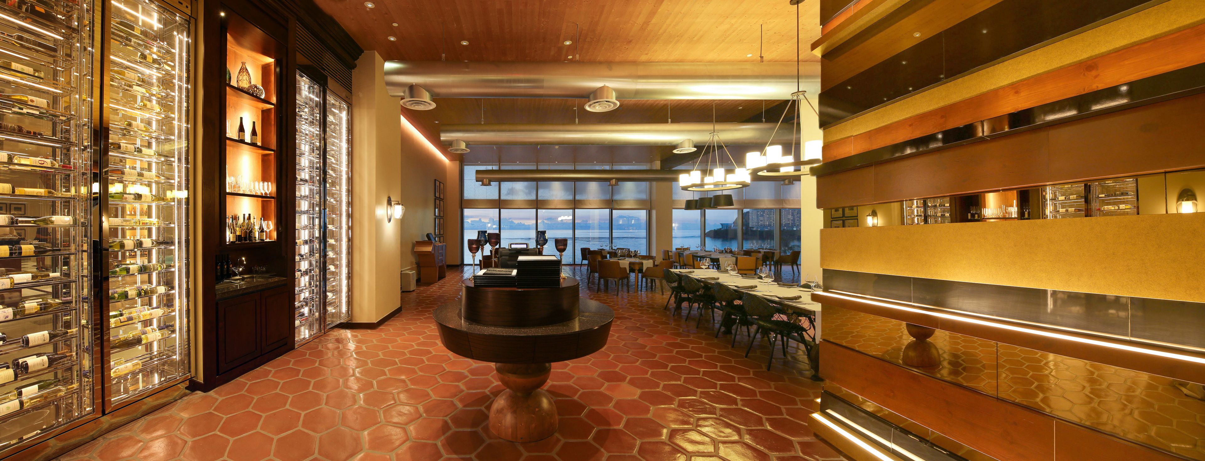 A bar area with a wine display, seating, and a view of the cityscape.