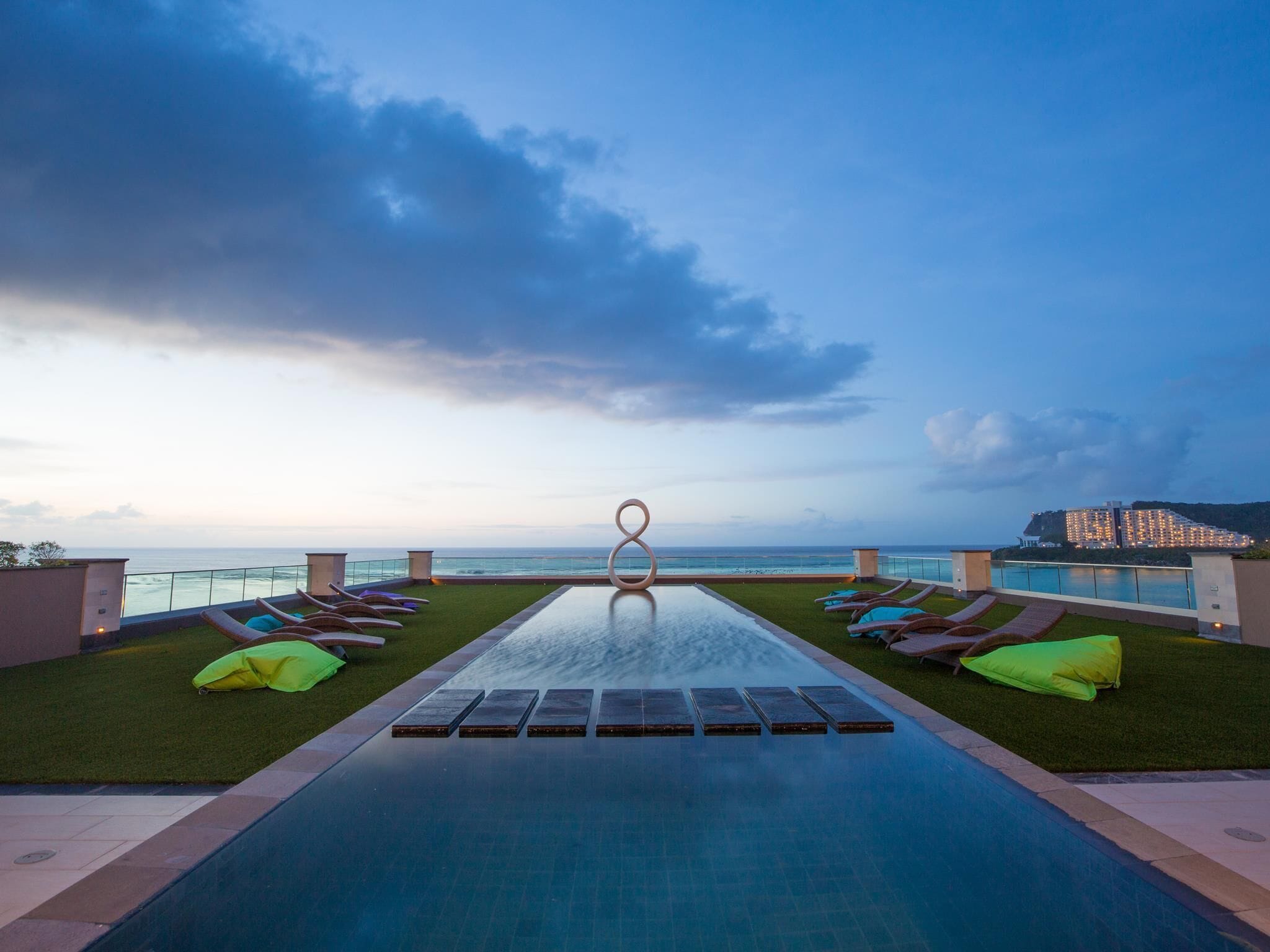 A infinity pool with a view of the ocean and a building in the background.