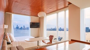A modern hotel room with a large bed, a dining table, and a view of the city skyline. - The Standard High Line (New York)