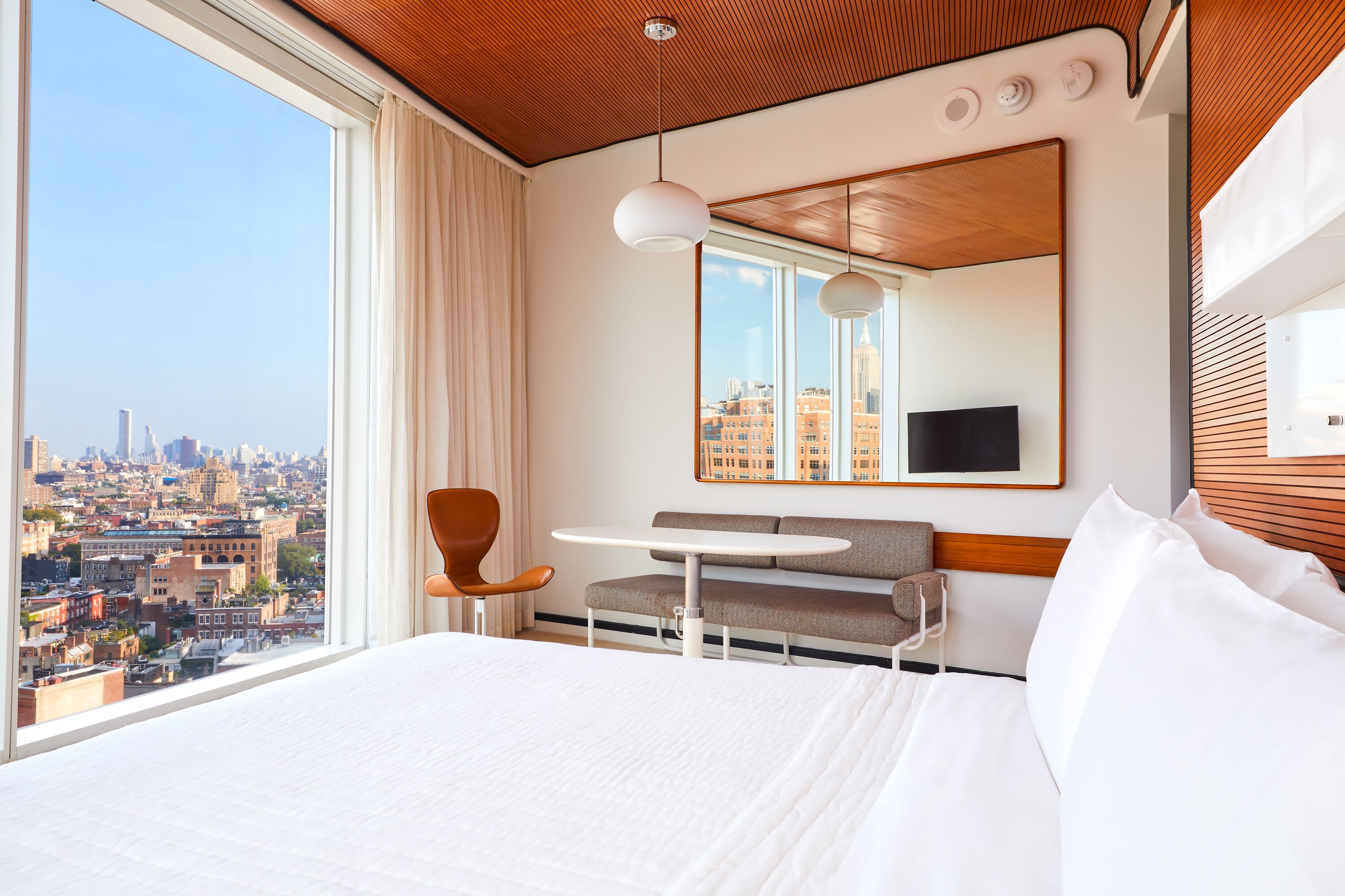 A hotel room with a large bed, a round table, a sofa, and a city view.