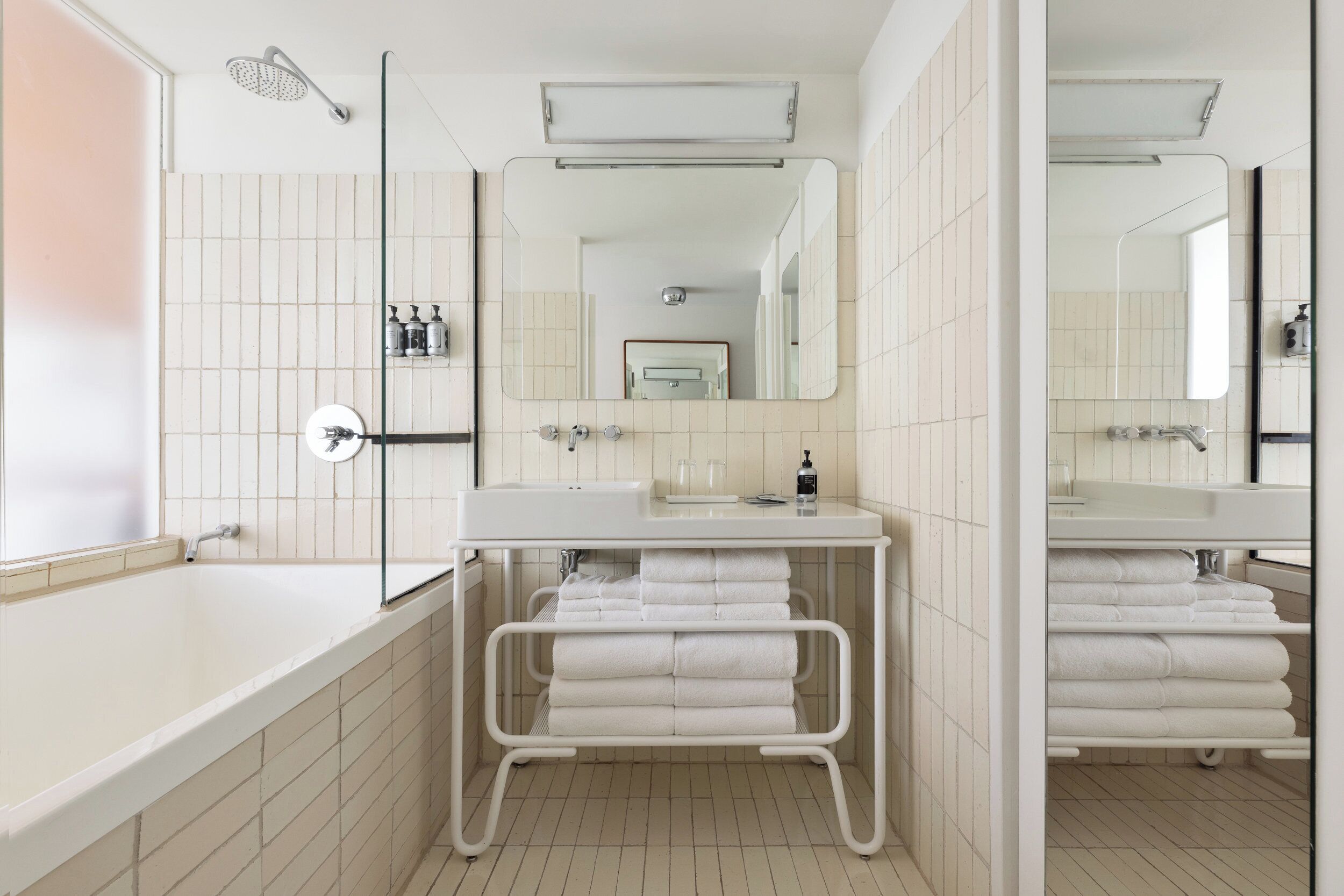 Un baño moderno con una bañera, dos lavamanos, un espejo y un perchero para toallas.