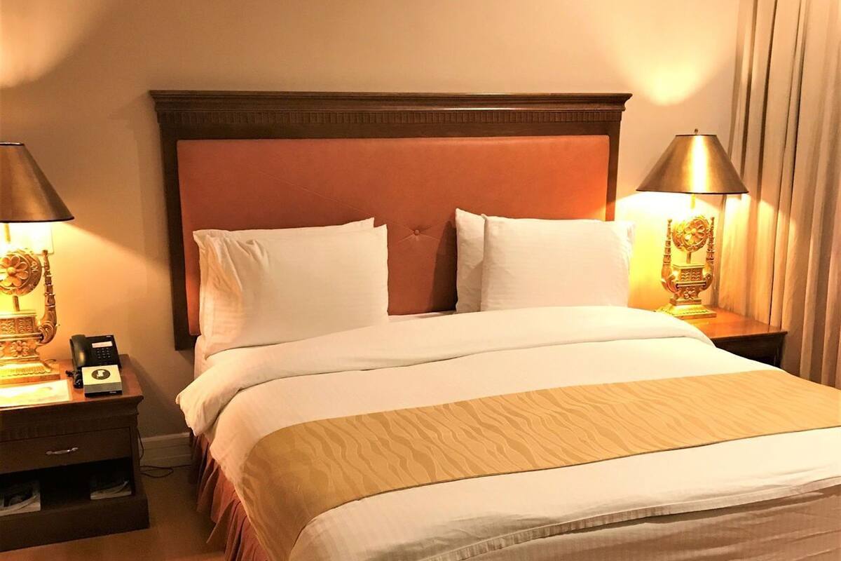 Une chambre d’hôtel avec un grand lit, deux tables de chevet avec des lampes et un plancher en bois.