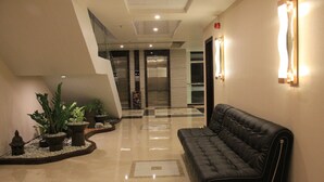 Eine moderne Lobby mit einer schwarzen Ledersofa, Topfpflanzen und einer Glastreppe.