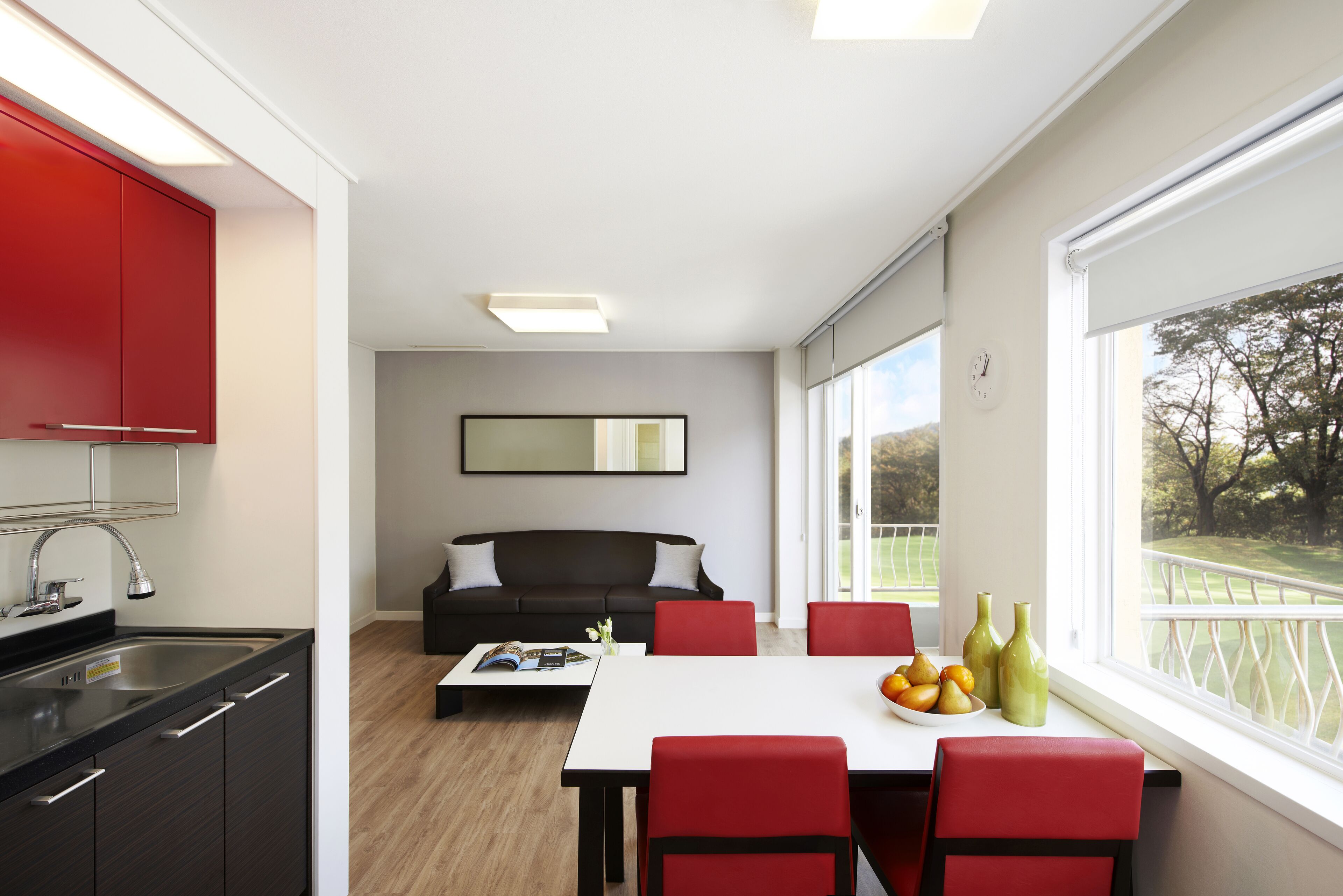 A modern kitchen with a dining area, a sofa, and a view of a golf course.