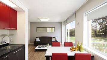 A modern kitchen with a dining area, a sofa, and a view of a golf course.