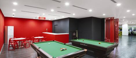 A pool table area with red chairs and a billiards table.