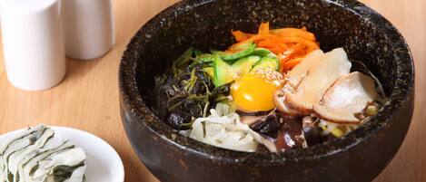 A bowl of food with various vegetables and a boiled egg on a wooden table.