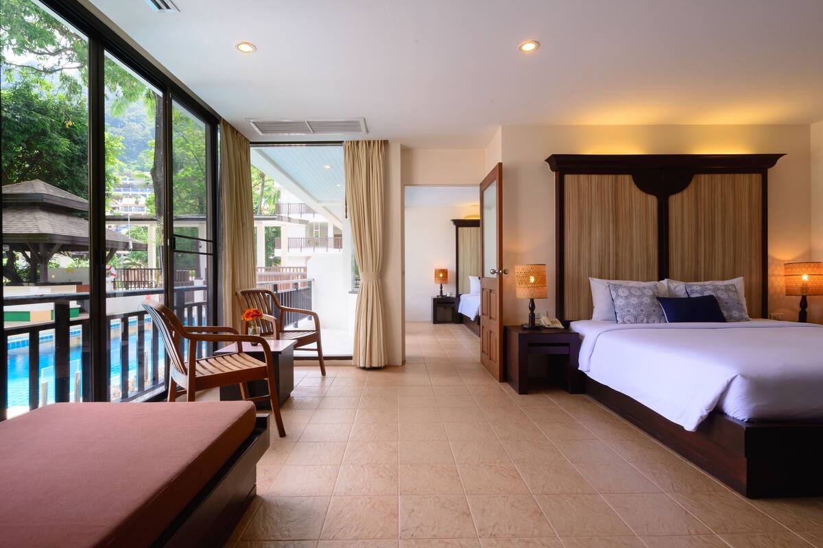 A hotel room with a bed, a desk, a chair, a view of a pool, and a balcony.