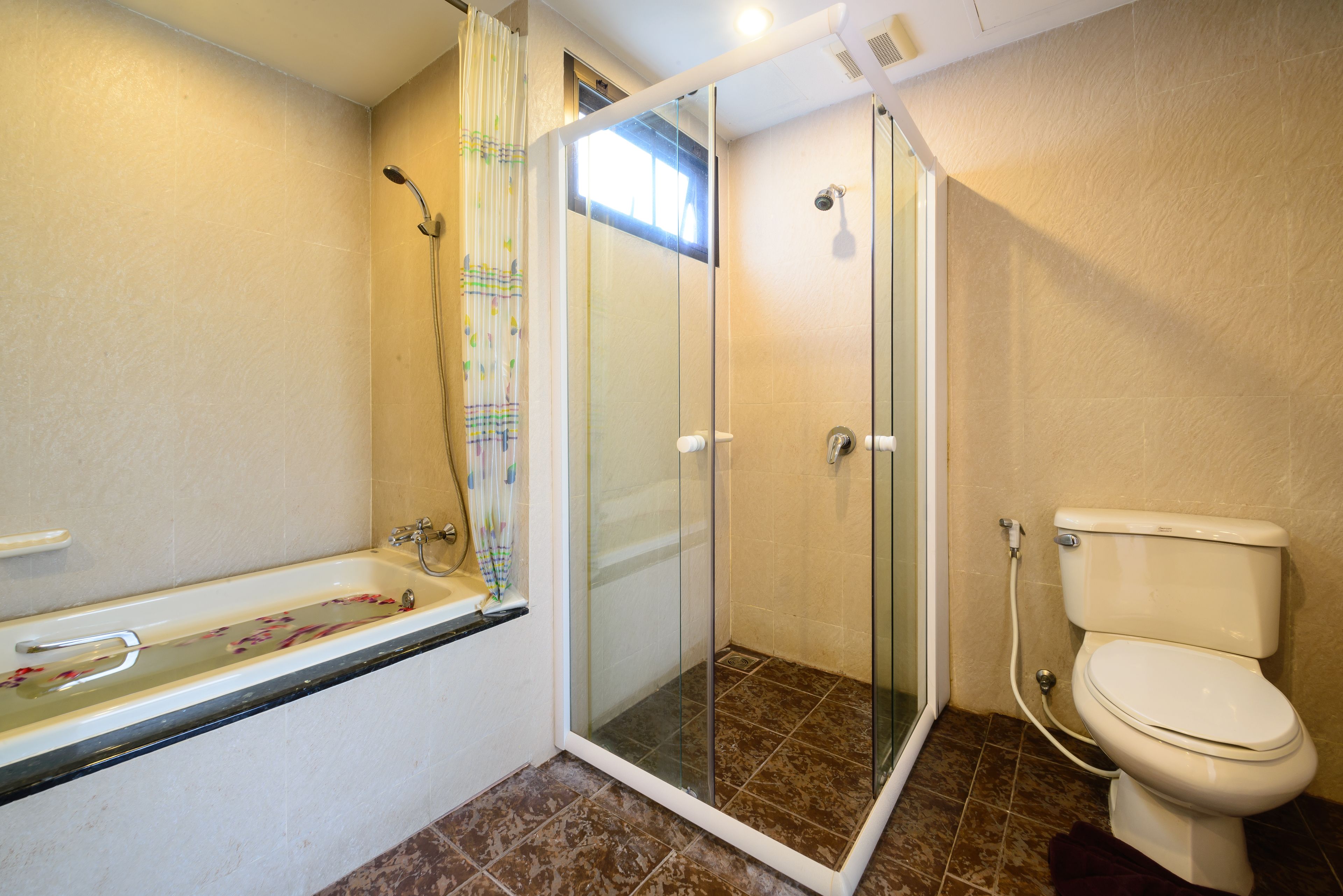 A bathroom with a glass-enclosed shower, a bathtub, and a toilet.