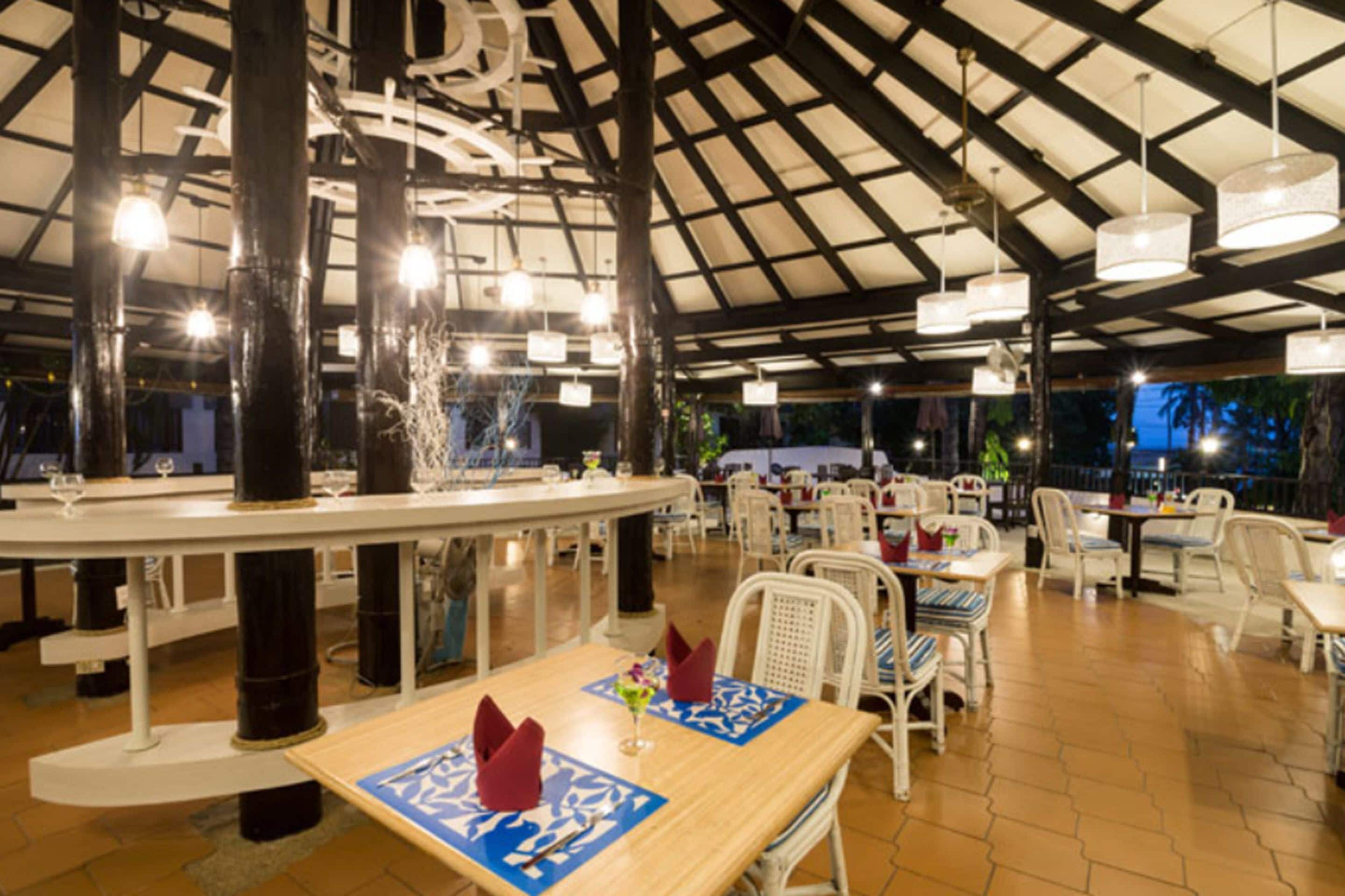 An indoor dining area with a high ceiling, white chairs, and tables.
