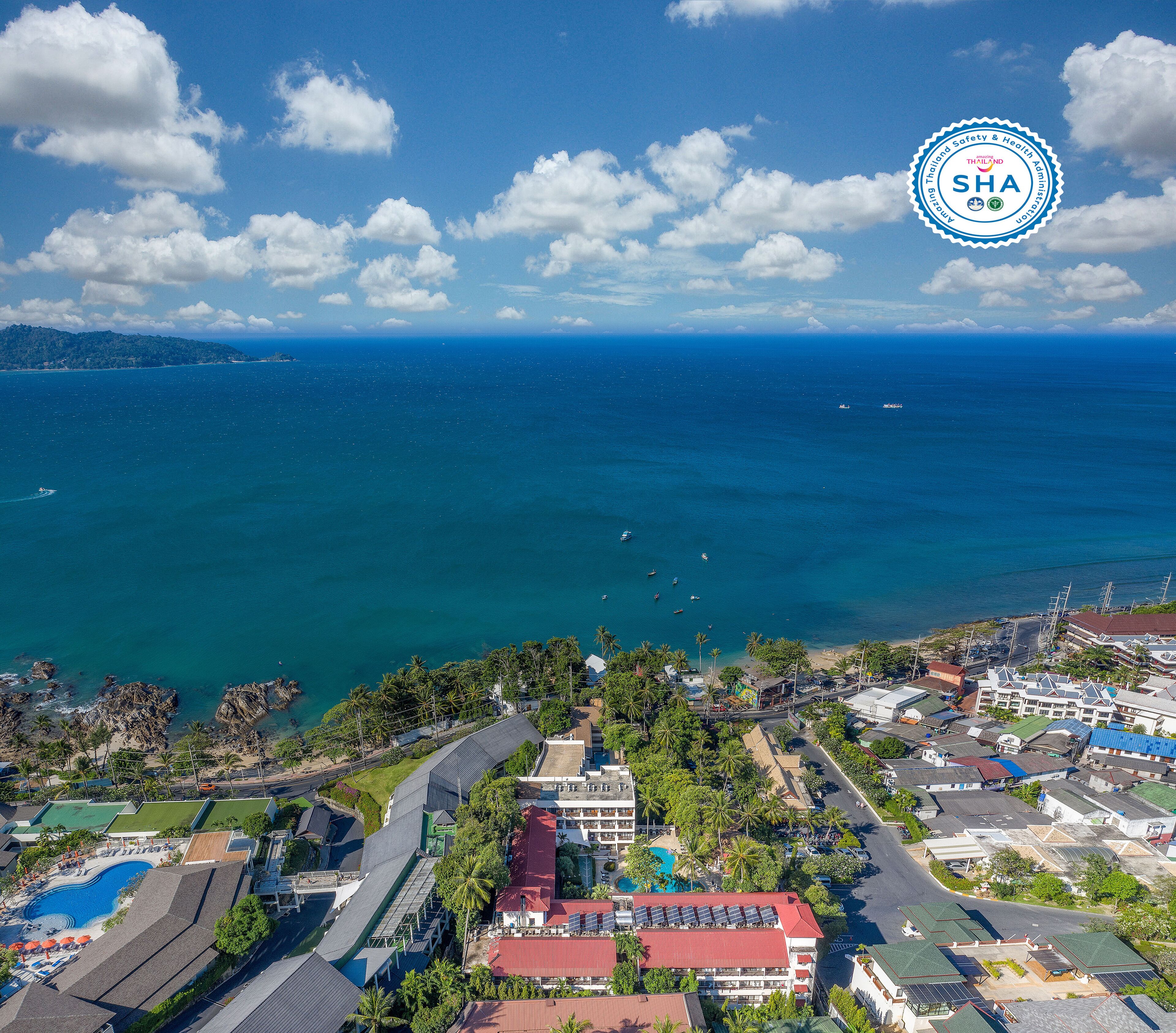 Vista aérea de una zona costera con un hotel que cuenta con varias construcciones, una piscina y vistas al océano.