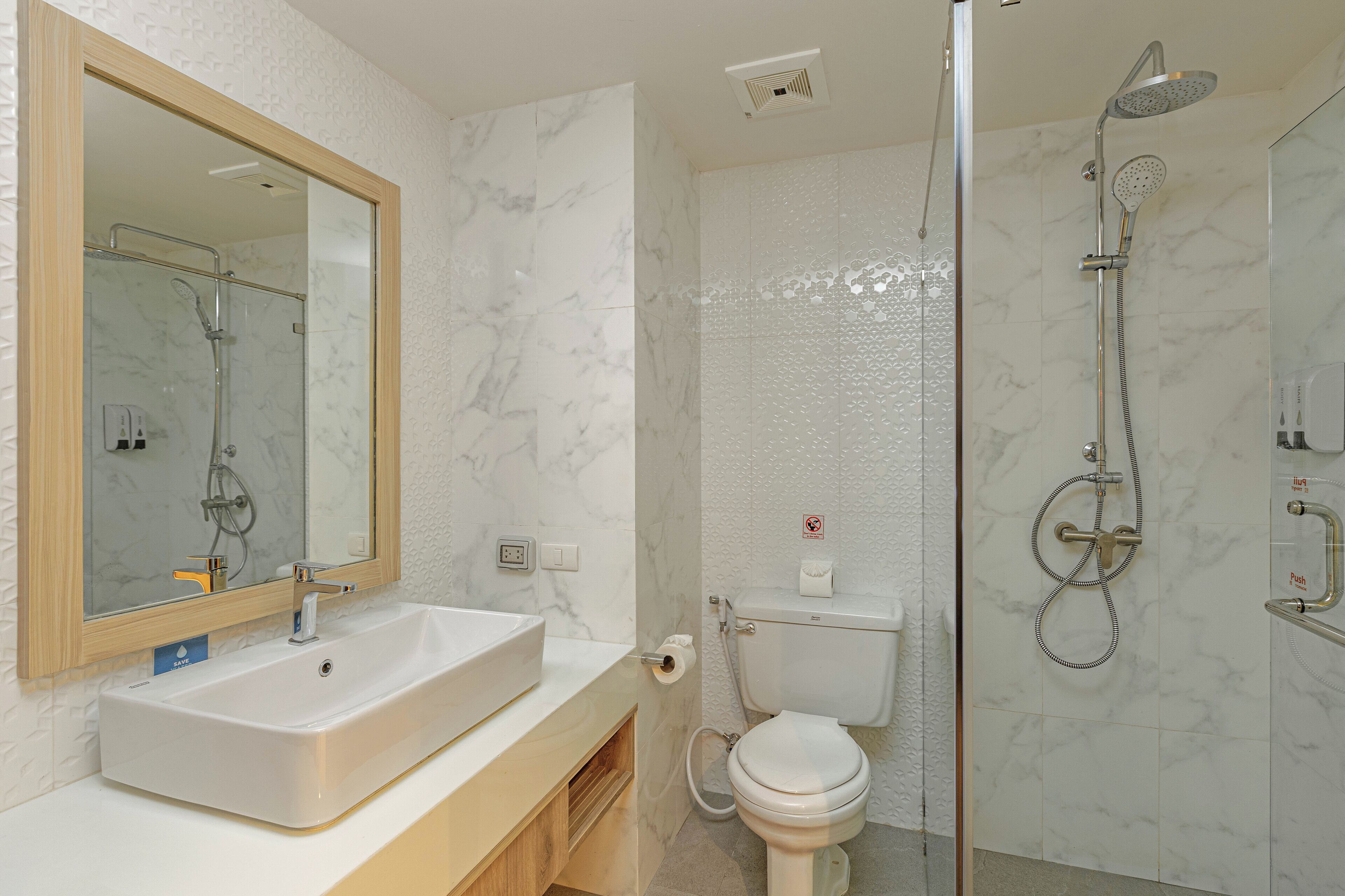 A bathroom with a marble sink, a mirror, a toilet, and a shower.