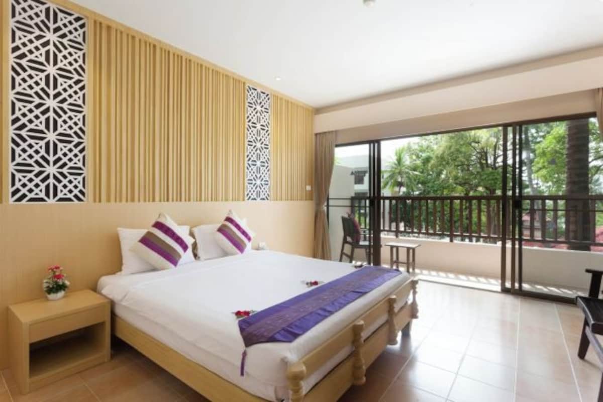 Habitación de hotel con una cama grande, una mesita de noche, un balcón con vistas a la vegetación y un diseño moderno con paneles de pared estampados.