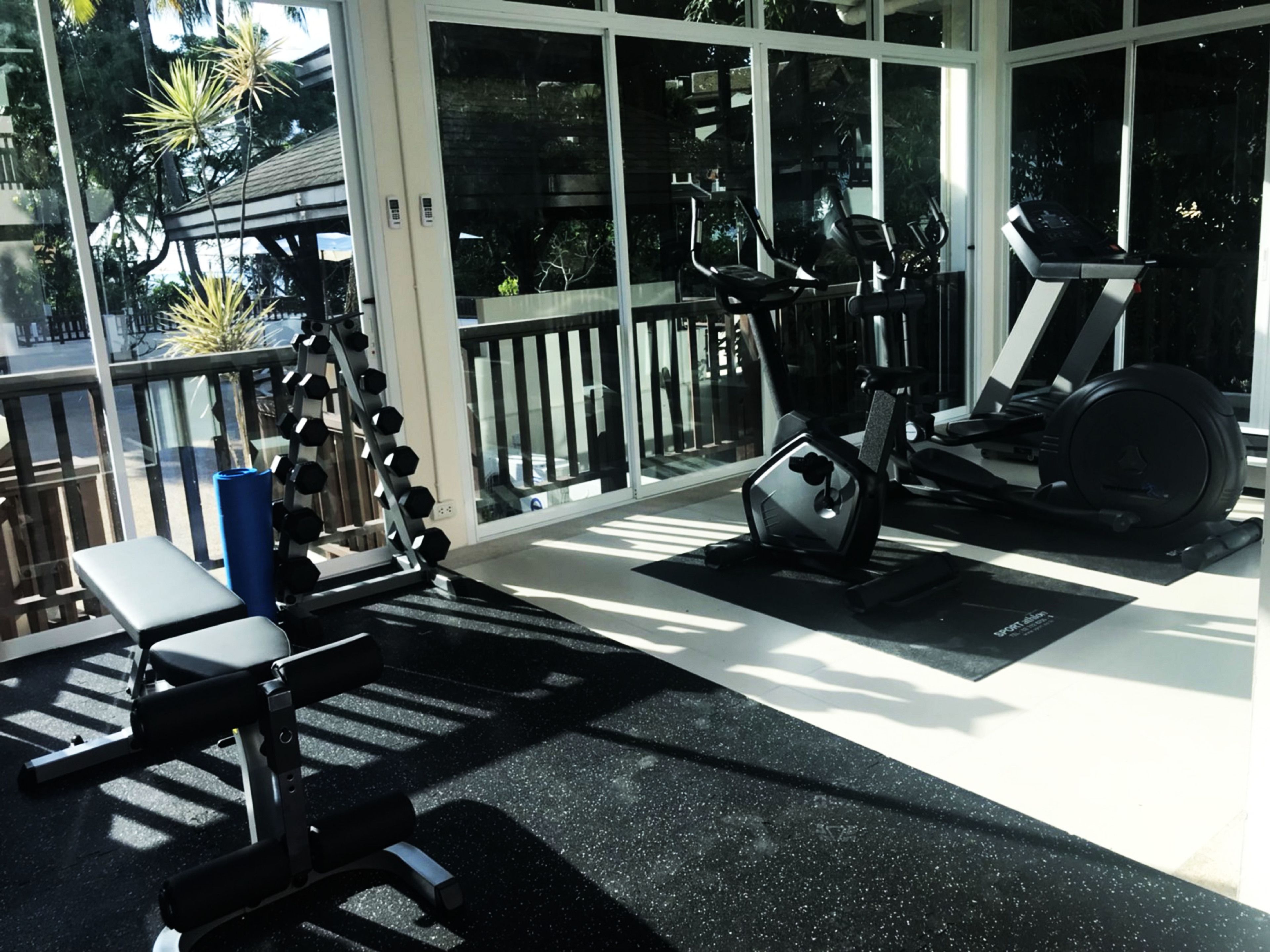 Un gimnasio con equipo cardiovascular, máquinas de pesas y una banca.