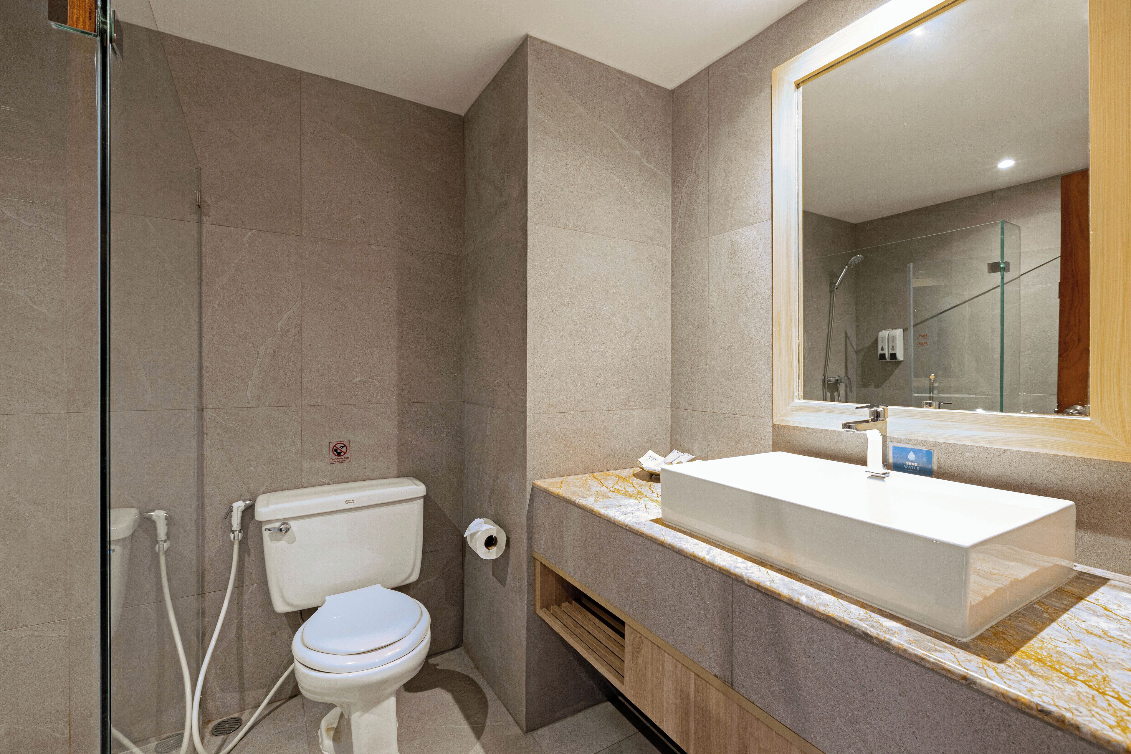 A modern bathroom with a glass shower enclosure, a toilet, and a sink with a marble countertop.