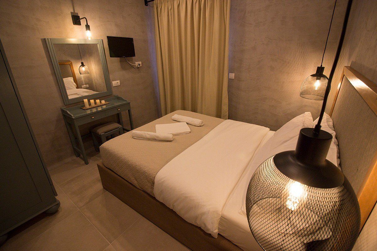A neatly arranged hotel room with a bed, a bedside table with a lamp, a mirror, and a curtain.
