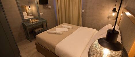 A neatly arranged hotel room with a bed, a bedside table with a lamp, a mirror, and a curtain.