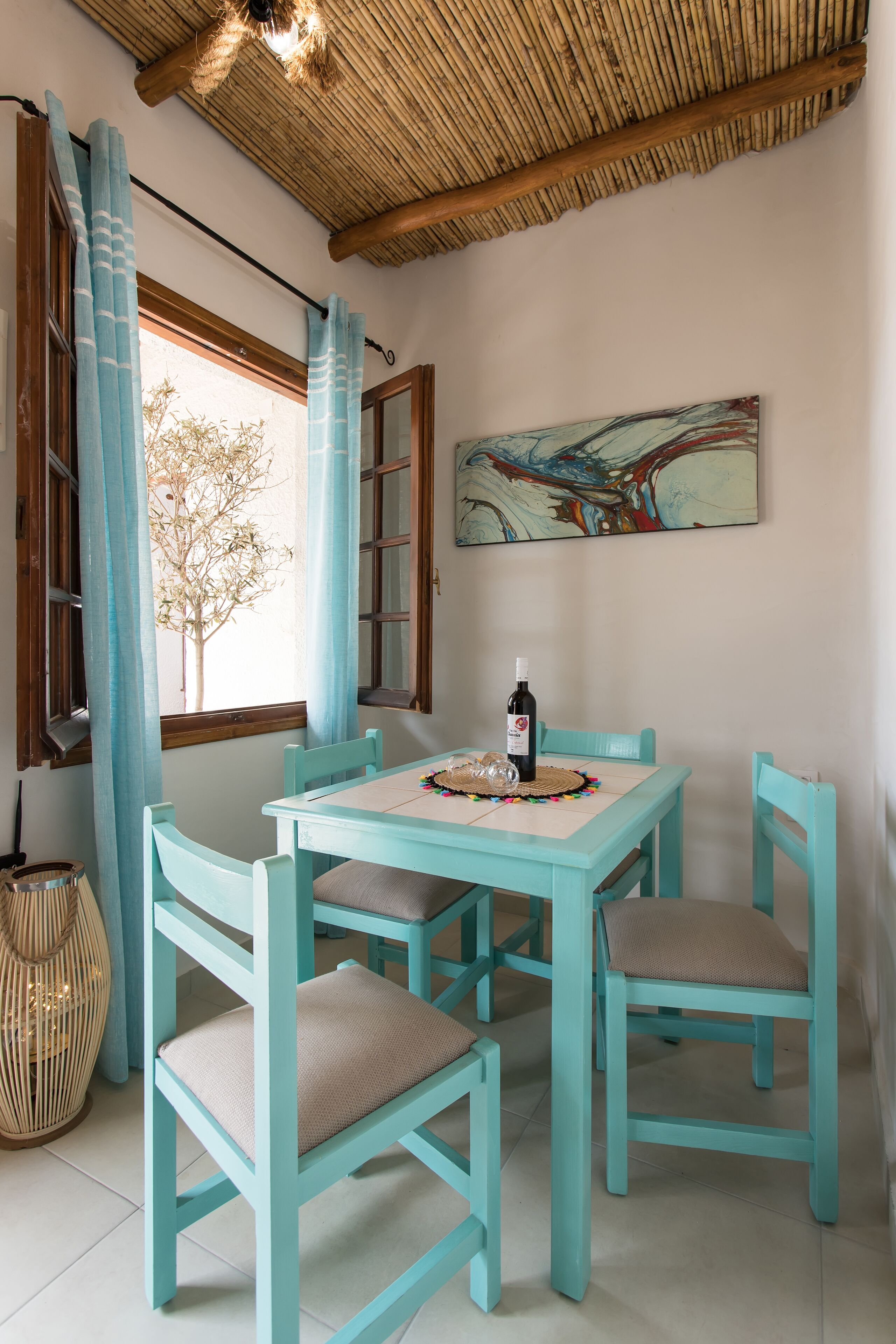 A dining area with a table and chairs, a bottle of wine, and a woven basket on the table.