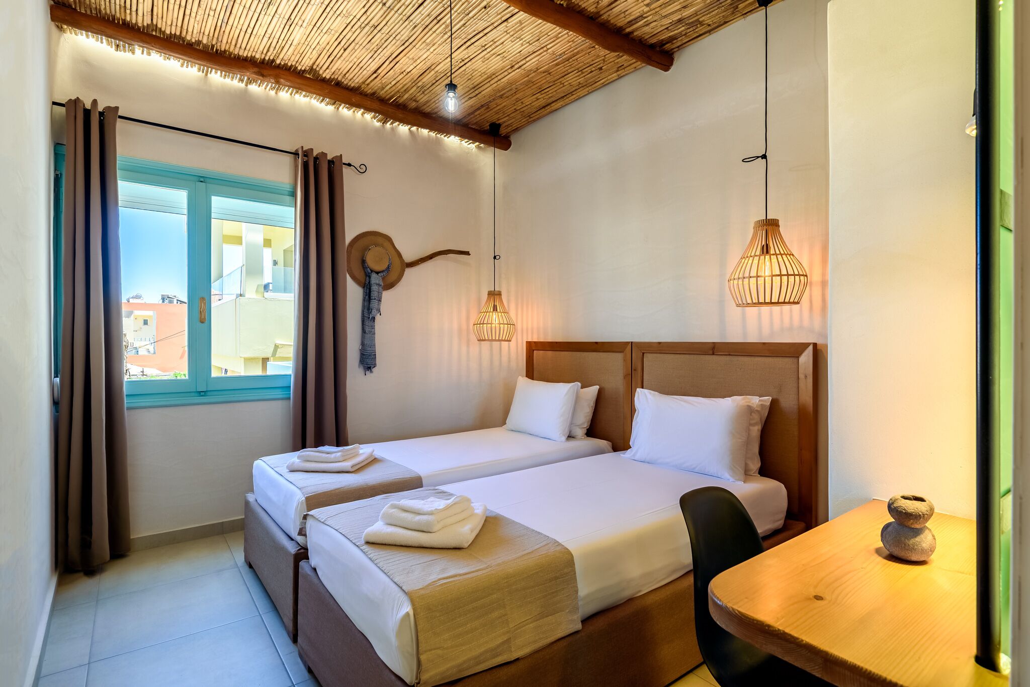 Habitación de hotel con dos camas, techo de madera y vistas al exterior.