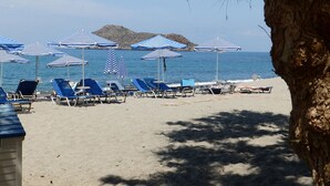 Una playa con hileras de sombrillas y tumbonas a rayas azules y blancas.