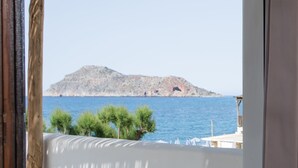 Vista de una isla rocosa en el mar desde un balcón con barandilla blanca.