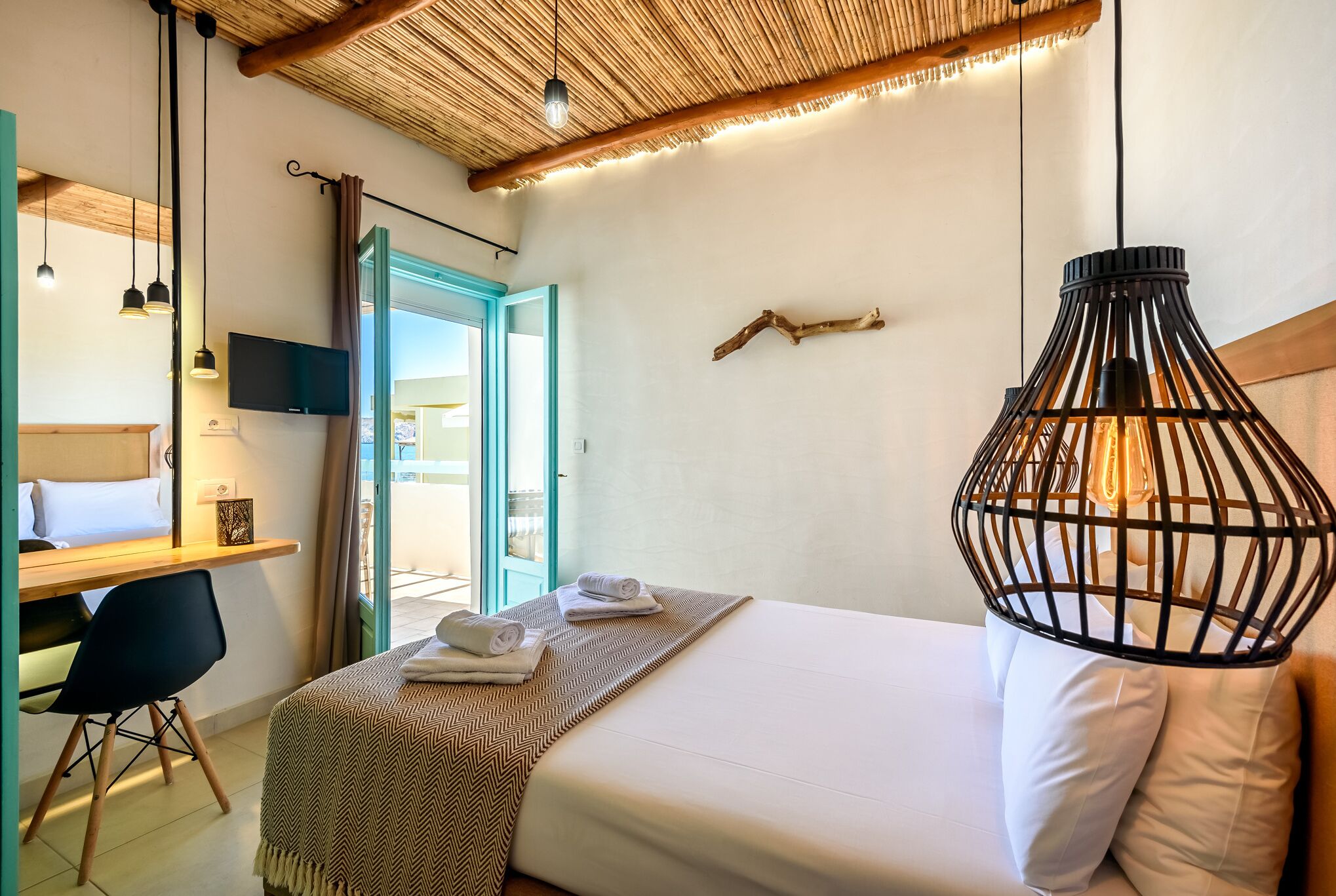Habitación de hotel con cama, escritorio con silla, televisión y ventana grande.