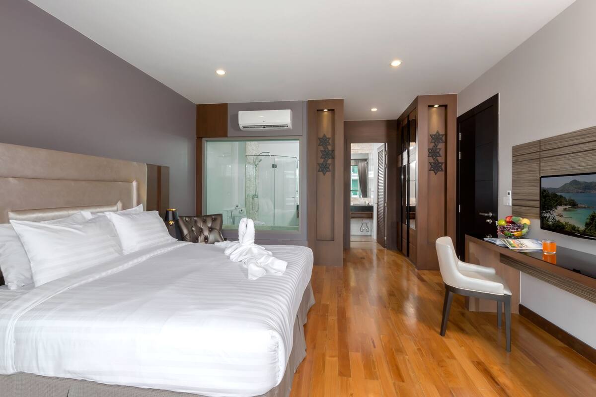 Une chambre d’hôtel moderne dotée d’un grand lit, d’un bureau avec une chaise, d’une télévision et offrant une vue sur la mer.