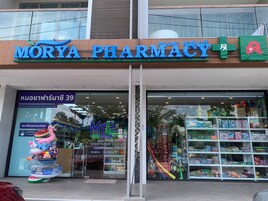 Uma farmácia chamada Morya Pharmacy com uma grande placa sobre a entrada.