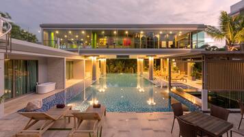 Una piscina techada, una piscina al aire libre, sombrillas