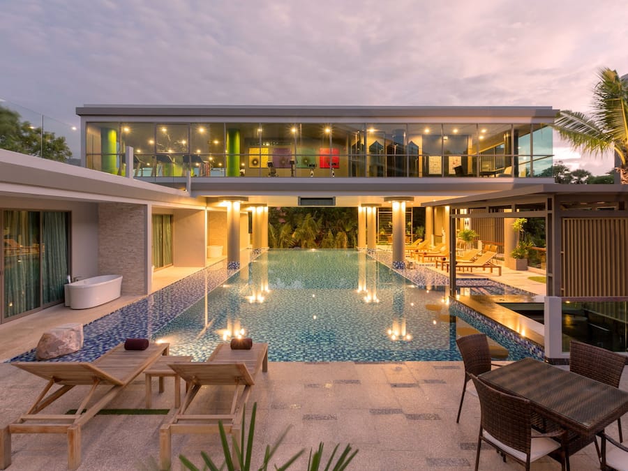Un hotel moderno con piscina en la azotea, sillones de descanso y zona de comedor.
