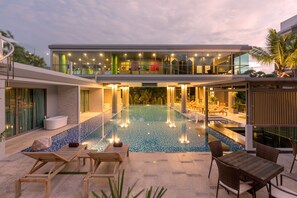 Een modern hotel met een zwembad op het dak, ligbedden en een eetgedeelte.