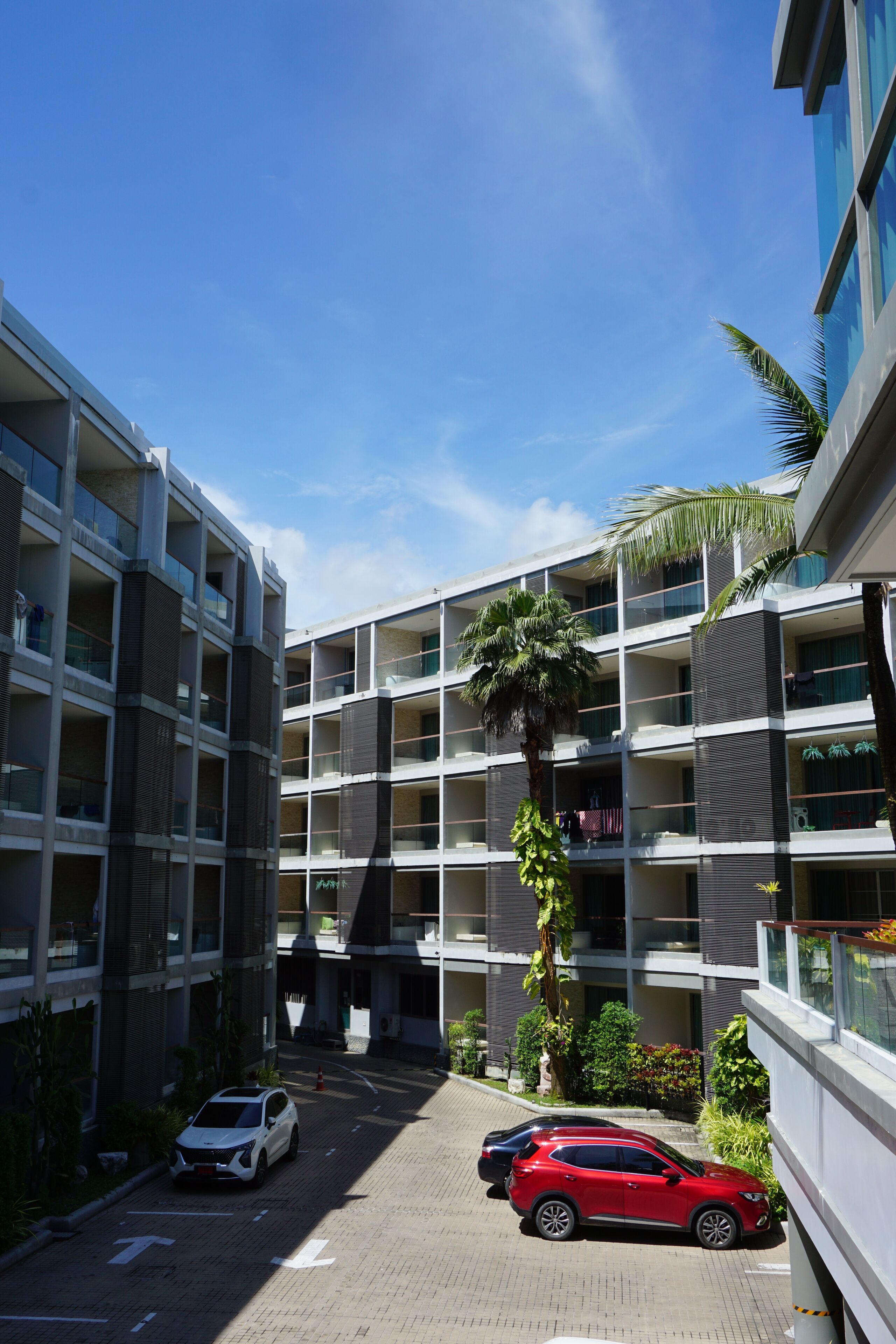 A multi-story parking garage with cars parked, surrounded by modern buildings and palm trees.