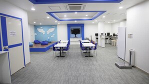Un espacio de oficina moderno con una paleta de colores azul y blanco, que incluye una zona de recepción, mesas de reunión y una báscula en el suelo.