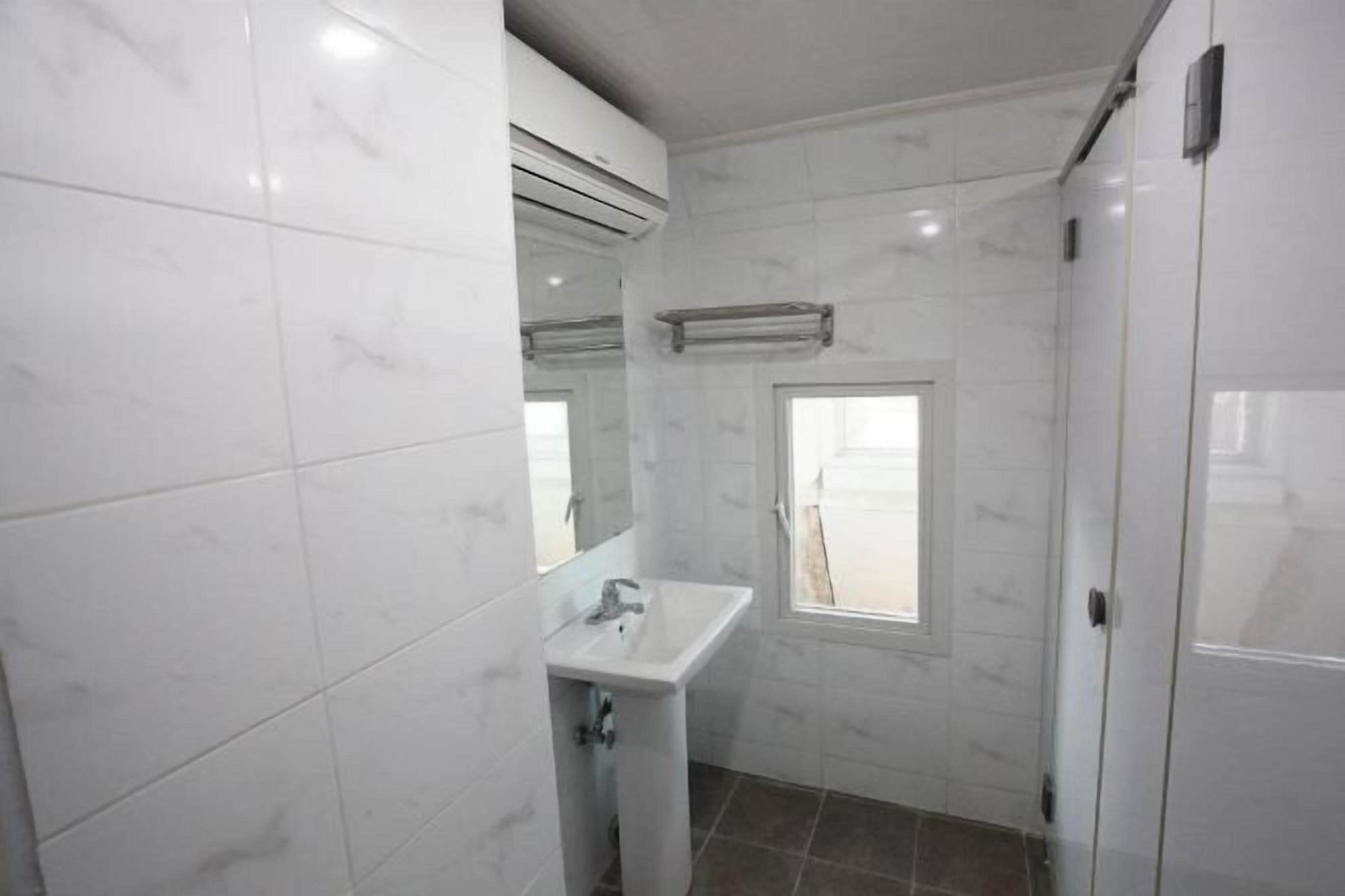 Badkamer | Een douche, een haardroger, pantoffels, handdoeken