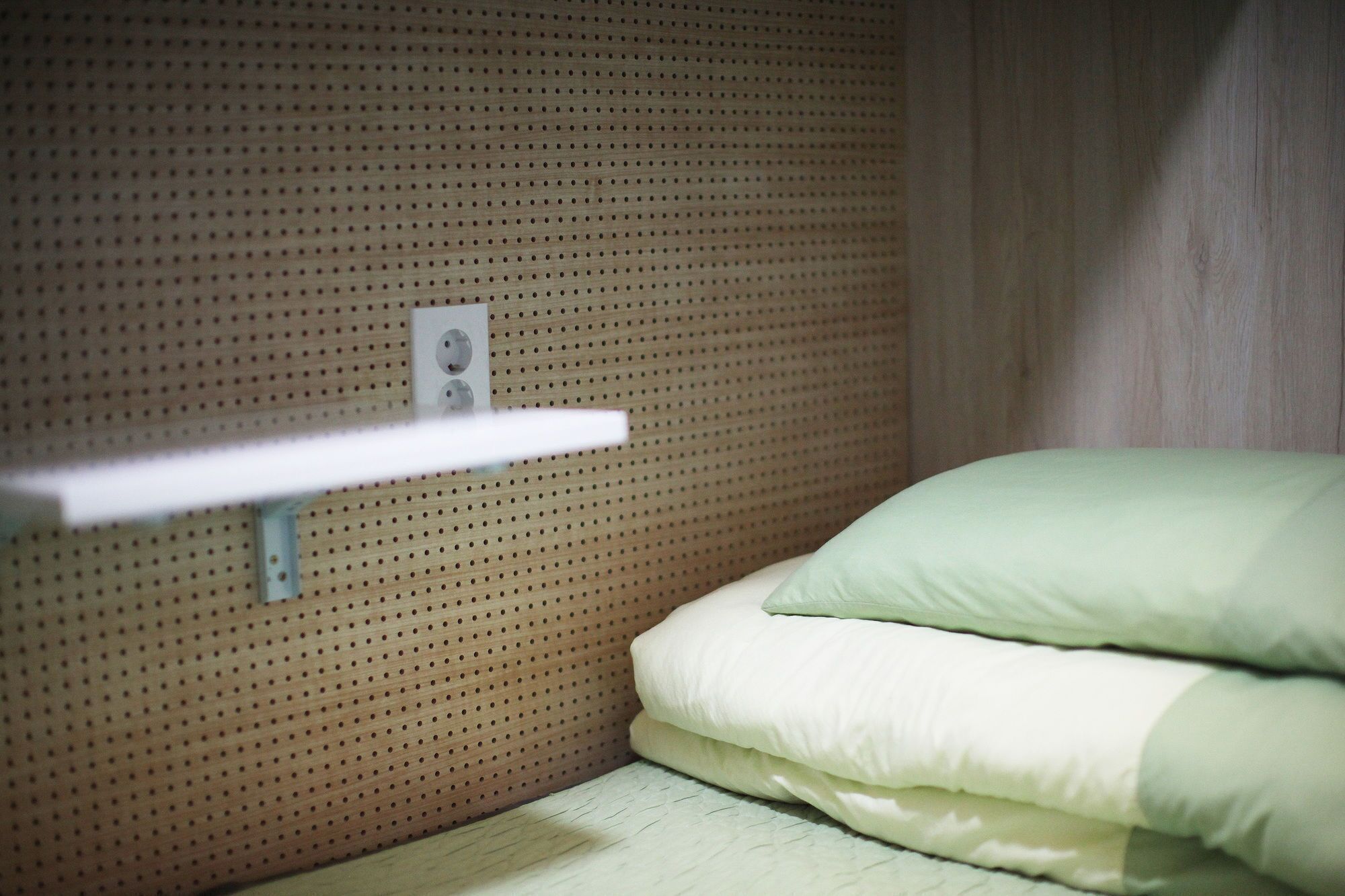 Una cama litera con un estante sencillo contra una pared de madera.