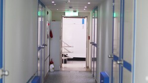 Un pasillo con taquillas, un extintor y una puerta que da a una habitación.
